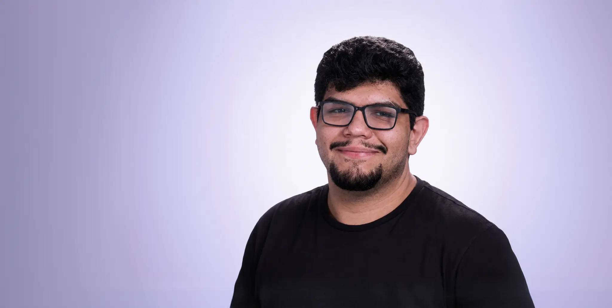 Jonathan Mendez, designer, de óculos e camiseta preta, sorrindo.