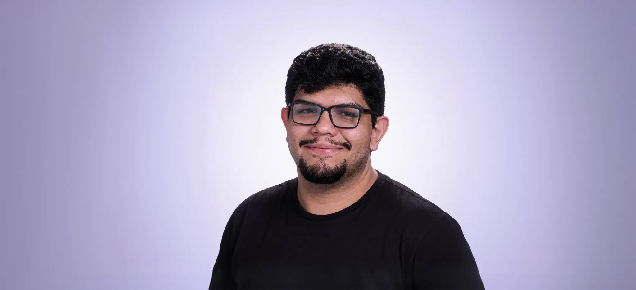 Jonathan Mendez, designer, de óculos e camiseta preta, sorrindo.
